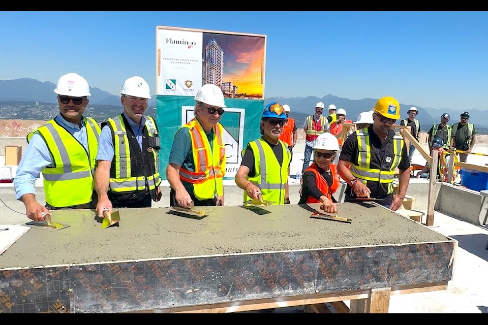 Construction company officials smooth freshly poured concrete during a "roof topping" ceremony at the Flamingo One tower in Surrey on Monday, July 8, 2024.