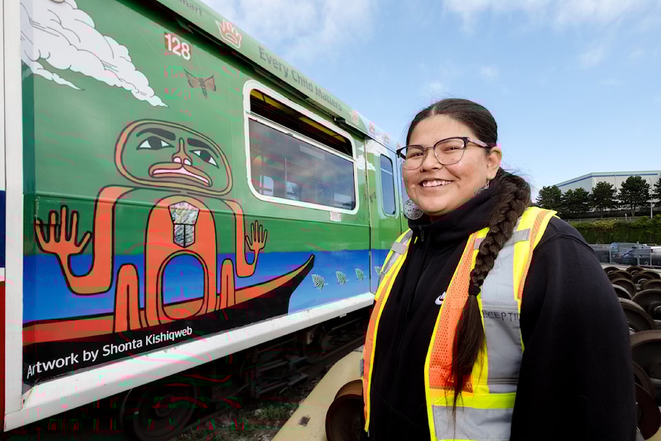 Artist Shonta Campbell (Kishiqweb) stands beside SkyTrain car art she created.