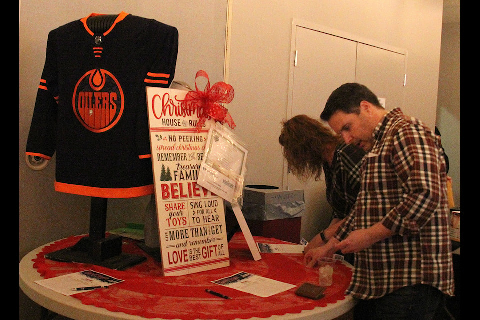 A couple of attendees at Spirit Night bid on a couple of silent auction pieces, including a signed Oilers jersey. Photos by Megan Roth/Sylvan Lake News