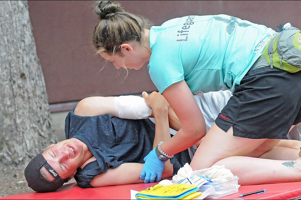 ‘Victim’ Elias Baker groans in simulated pain as lifeguard Amanda Renardy tends to him at the Walnut Grove Pool, scene of the 20th annual Langley lifeguard competition. (Dan Ferguson/Langley Advance Times)