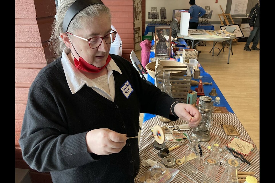 Before the onslaught of video games, young people found other ways to amuse themselves. Here, Terrace Regional Historical Society president Leah Harris, demonstrates a spinner. It was just one of many items from bygone years on display at the Heritage Day event held Feb. 25 at the Sportsplex banquet room. (Staff photo)
