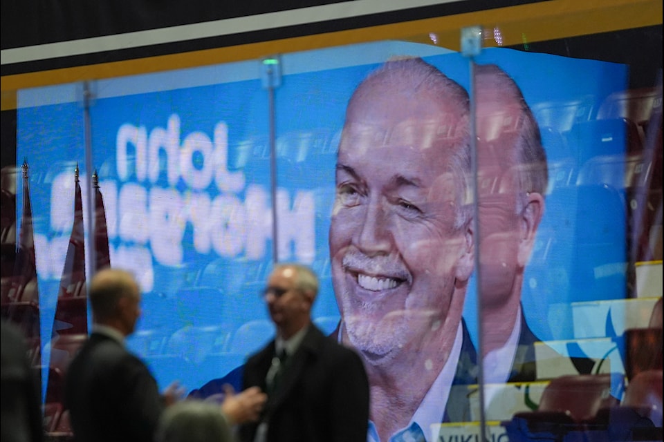 A photograph of former British Columbia premier John Horgan displayed on a screen is reflected in arena glass as people gather for a state memorial service for Horgan, in Colwood, B.C., on Sunday, December 15, 2024. Horgan, Canada's ambassador to Germany and a former NDP premier who formed a minority government in 2017, died last month after his third bout with cancer.