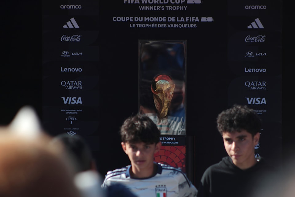 Fans pose for a photo in front of the FIFA World Cup winner's trophy which was on display at the Italian Cultural Centre in Vancouver Tuesday (Aug. 26, 2025).