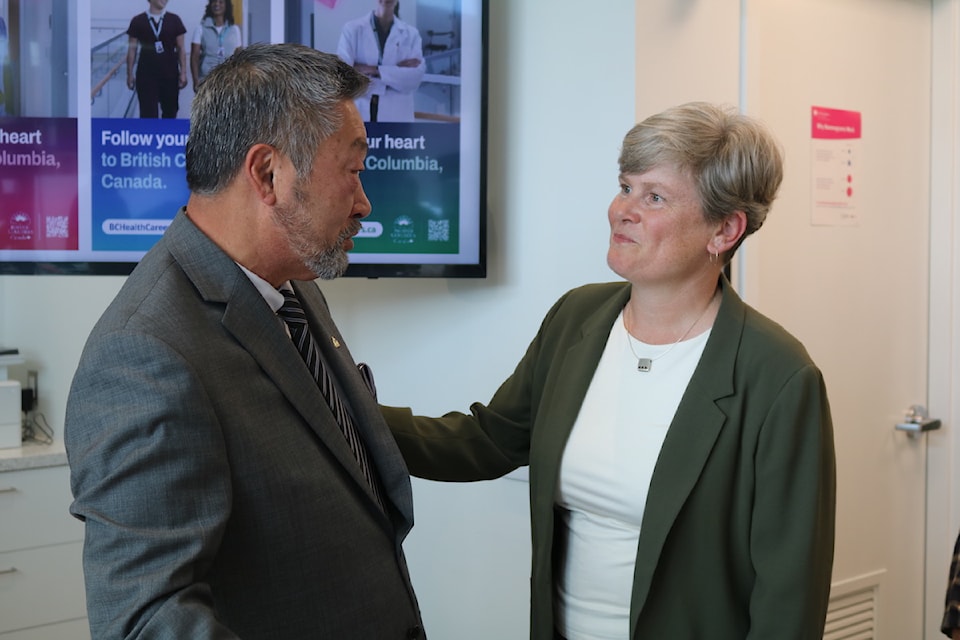 Health Minister Josie Osborne speaks to Colwood Mayor Doug Kobayashi at an announcement about health-care worker recruitment on June 6, 2025.
