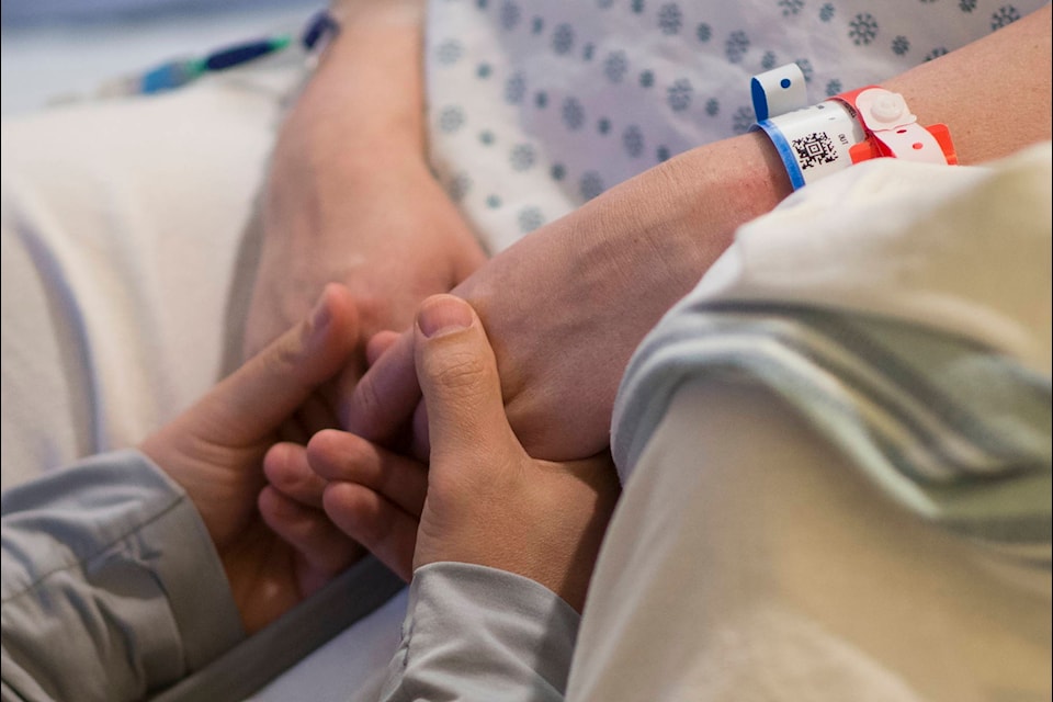 Brian Chong holds wife Kate’s hands as she speaks to the anesthesiologist at St. Paul’s hospital in downtown Vancouver, Saturday, June 13, 2020. THE CANADIAN PRESS/Jonathan Hayward