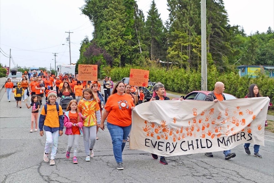 Ucluelet Secondary School principal Carol Sedgwick, centre, walks in solidarity with Nuu-chah-nulth residential school survivors, their families and local supporters during a walk in Ucluelet on Sunday. (Nora O’Malley photo)