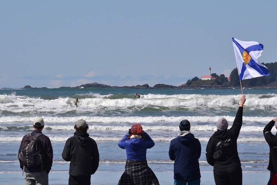 EAST COAST CREW: Mom Lisa Scott flies the Nova Scotia flag as her daughter Juniper Balch, front in the yellow jersey, and Tofino’s Chloe Platenius ride waves during the semi final of the Under 16 Girls division at Cox Bay on Sunday. (Nora O’Malley photos)