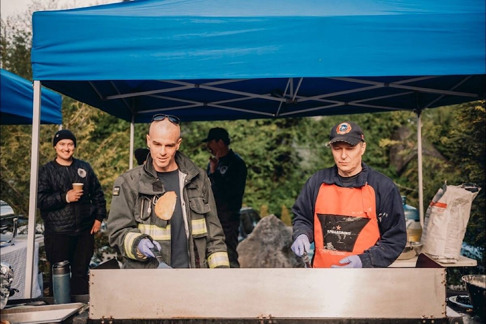 Ucluelet Fire Rescue (UFR) member Dan Lehr tosses a pancake beside veteran volunteer firefighter Alan Anderson (who came out of retirement to help with the event!) (Jen McLeod Photos)