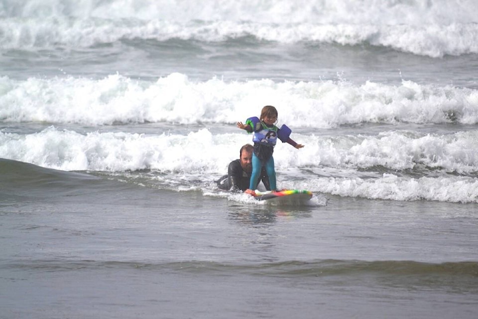 BEACH DAYS ARE THE BEST: Little Juniper Newman, 3, and dad Pete catch a wave during an expression session at the Sept. 24 Bruhwiler Kids Classic Surf Classic at Cox Bay. See more photos of the fun beach day on Page 15. (Nora O’Malley photos)