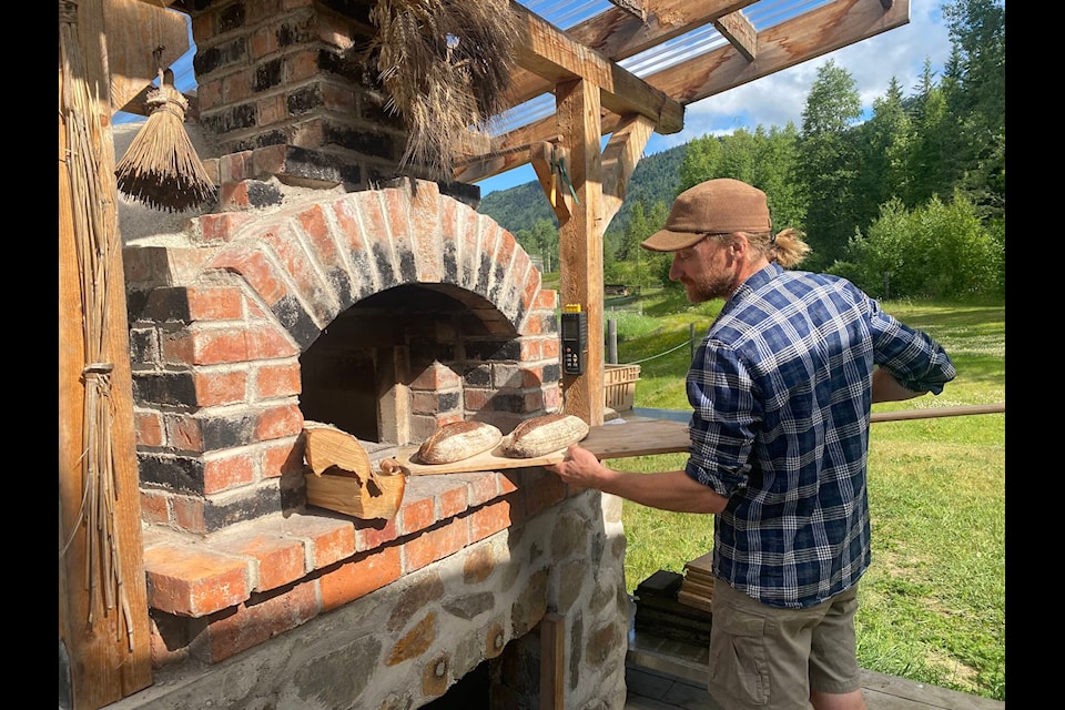 Jonathan Knight pulls out two loaves of bread from his hand-built wood fired oven, after harvesting his wheat fields and grinding the wheat on his also hand-built stone ground mill. He runs his farm, WoodGrain Farm, with his partner, Jolene Swain, up in Kispiox Valley, where together they produce vegetables, seeds, flour, lamb and garlic salts. (Photo by WodGrain Farm)