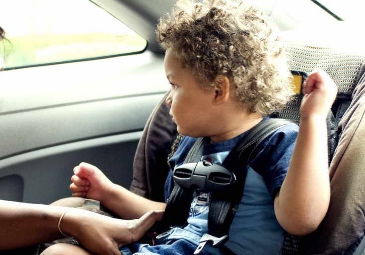 Young son into his back seat located child safety seat