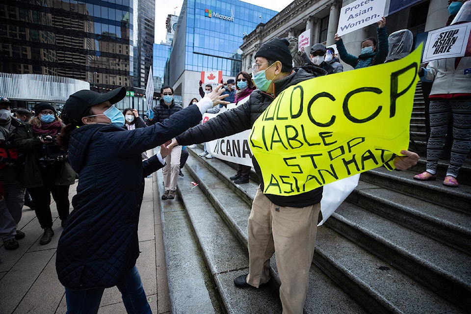 A man, right, who was holding a sign that said “Hold CCP Liable” disrupts a peaceful rally opposing discrimination against Asian communities and to mourn the victims of those affected by the Atlanta shootings, in Vancouver, B.C., on Sunday, March 28, 2021. After a brief scuffle the man was escorted to an area away from the crowd by police. THE CANADIAN PRESS/Darryl Dyck