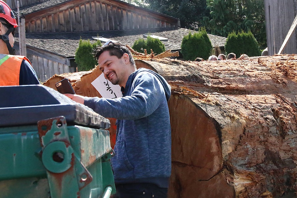 Spotting his name stapled to the 15,000 pound log, carver Luke Marston takes a quick selfie with his phone. (Lexi Bainas/Citizen)