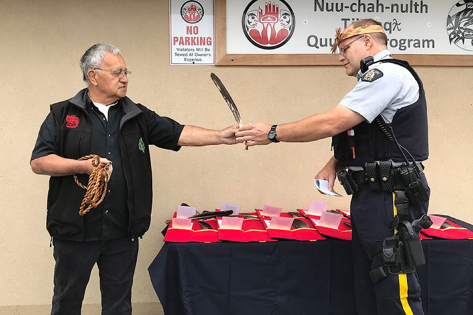 Joseph Tom, senior cultural worker with the Nuu-chah-nulth Quu?asa program in Port Alberni, hands an eagle feather to Port Alberni RCMP Cst. Pete Batt during a blessing ceremony on Friday, June 5, 2020. The RCMP will use 12 feathers to help them better communicate with Indigenous people in the community. (SUSAN QUINN/ Alberni Valley News)