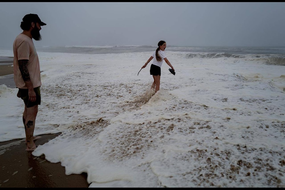 Ryan Madigan, and his daughter Charolette Madigan, 11, of Cold Spring Harbor, N.Y., stand along a beach in Montauk, N.Y., Saturday, Aug. 21, 2021, as Hurricane Henri churns up waves as the storm approaches. (AP Photo/Craig Ruttle)
