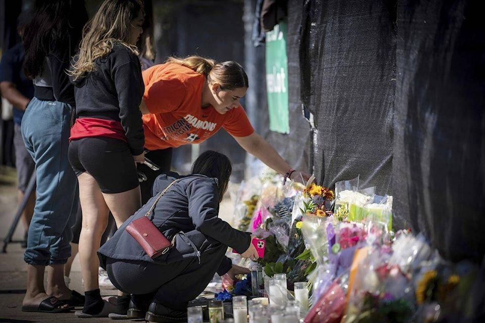 Stacey Sarmiento places flowers at a memorial in Houston on Sunday, Nov. 7, 2021 in memory of her friend, Rudy Pena, who died in a crush of people at the Astroworld music festival on Friday. (AP Photo/Robert Bumsted)