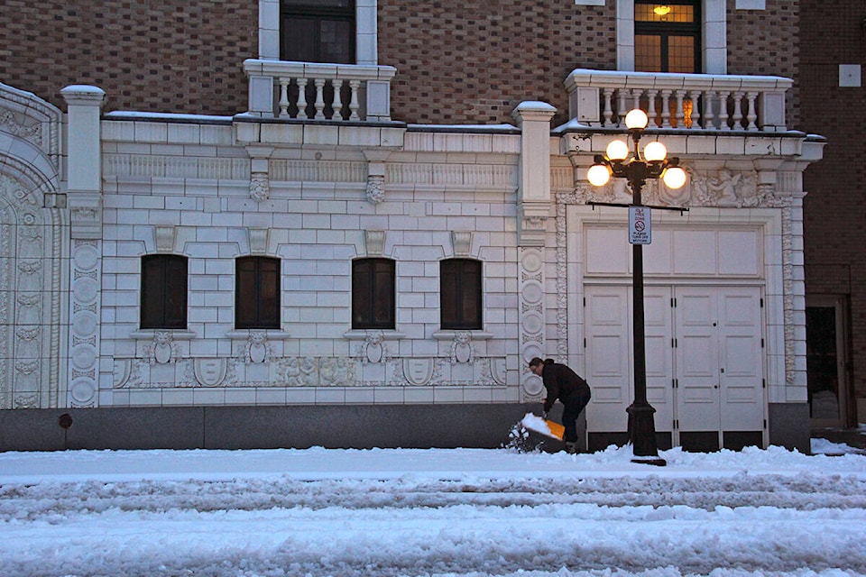 A woman shovels snow off the sidewalk outside the Royal Theatre on Broughton Street on the morning of Jan. 6. (Jane Skrypnek/News Staff)