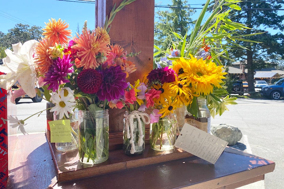 A collection of flower offerings sits on a ledge outside the Metchosin Country Store, in the wake of the death of co-owner Adriana Ko. (Cathy Webster/Black Press Media)