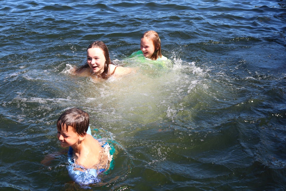 From left to right: Skylar Baranieski, London and Leighton Chalmers enjoy a dip in the water off the new floating dock at Langford Lake on July 21. (Bailey Moreton/News Staff)