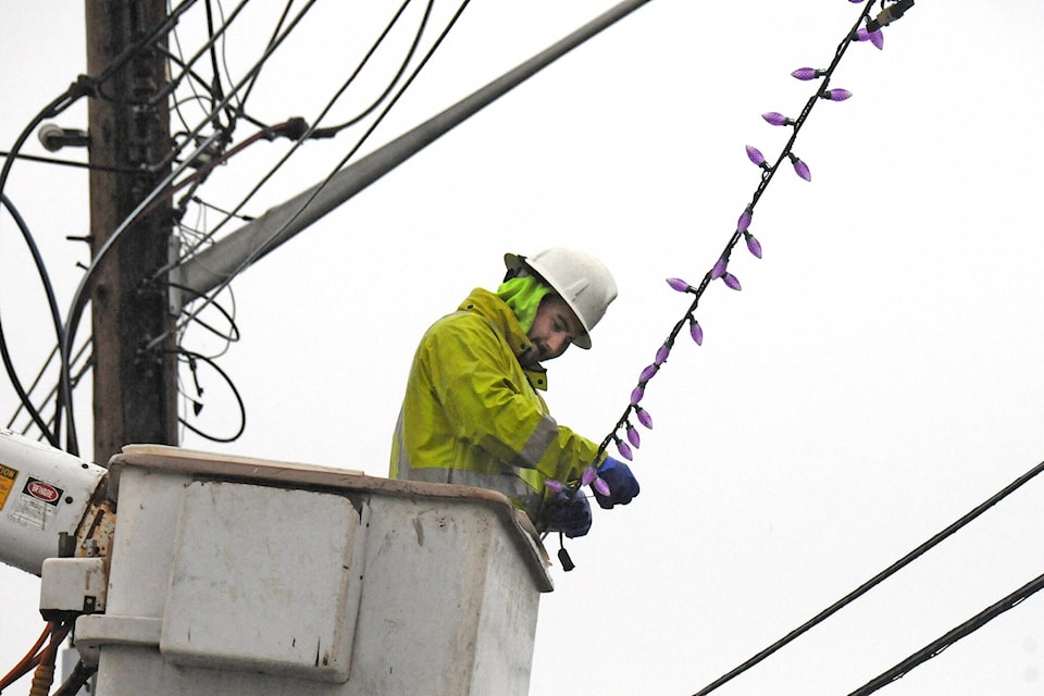 Wade Addy from Addy Power Ltd. in Errington hangs Christmas lights across the bottom of Johnston Road in Port Alberni on a stormy Tuesday, Nov. 24, 2020. (SUSAN QUINN/ Alberni Valley News)