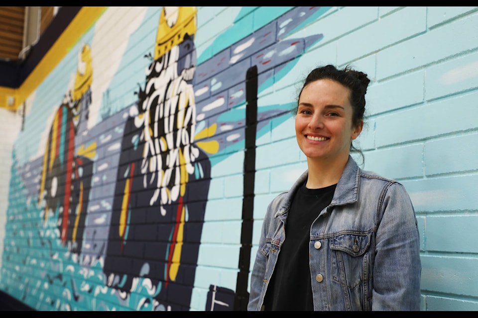 Jessica Wiebe standing in front of the mural she has created for Nechako Valley Secondary School. (Aman Parhar/Omineca Express)