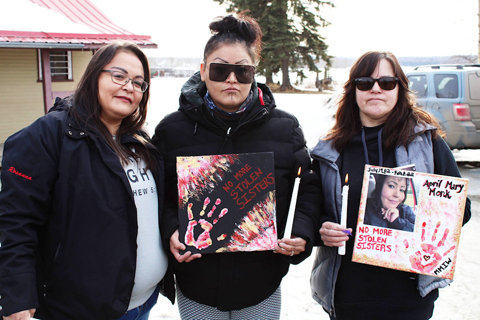 Women hold up signs reading ‘no more stolen sisters’ at a vigil for April Mary Monk at Spirit Square in Fort St. James. (Photo by Michael Bramadat-Willcock)