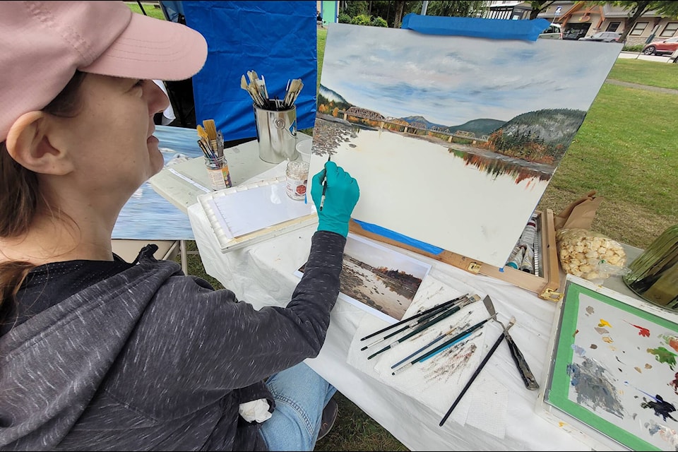 Rachel Mohr, one of the 22 artists participating in the Terrace Art Gallery’s Artists in the Park event on Aug. 12, focuses on her painting during the Riverboat Days festival, showcasing her creative process to intrigued onlookers. (Submitted photo)