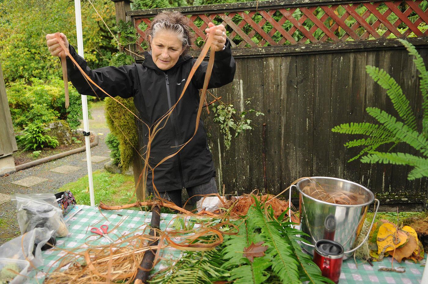 Fran Quinlan with Choreography of Trust, an international collective of women artists, peels apart cedar bark at Cultus Lake on Tuesday, Sept. 26, 2023. (Jenna Hauck/ Chilliwack Progress)