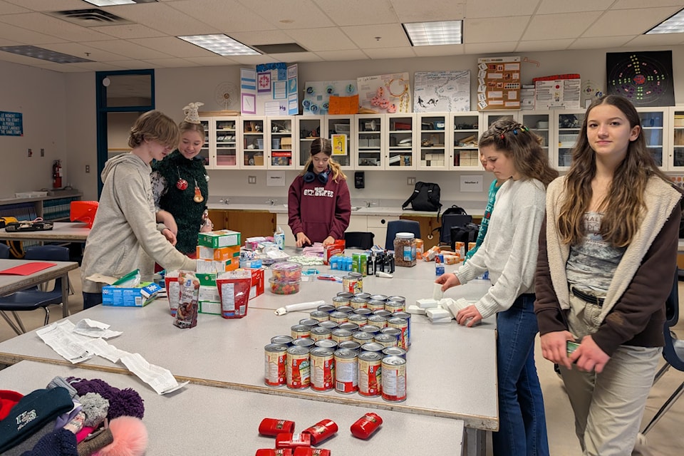 Sebastian Inkster, Thea Kicksee, Julie Colver, Ruah Kim (hidden), Emily Schwartz and Sophia Zerrath sort goods to fill backpacks donated to those in need.