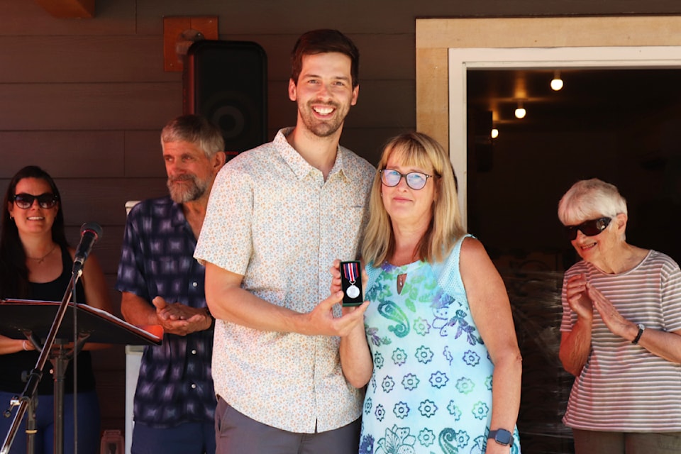Nick Johnson (left), manager of member services at Food Banks BC, hands Sharon Harvey of Cherryville Community Food and Resources the King Charles III Coronation Medal at an event at the food bank Saturday, Aug. 9, 2025. 