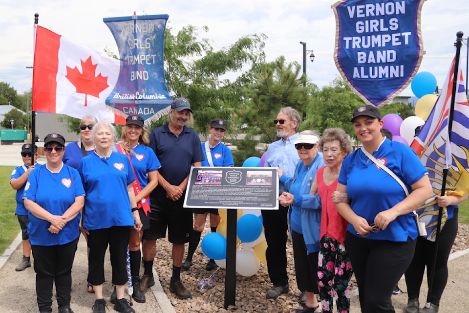 Left to right: Vernon Girls Trumpet Band member Di Towpich, band leader Cam Condi, Randy Rigby, June Rigby, Phyllis Scott and band member Bobbie-Jo Thompson, all standing around a plaque honouring the Trumpet Band that was unveiled in Civic Memorial Park Saturday, July 5, 2025. 