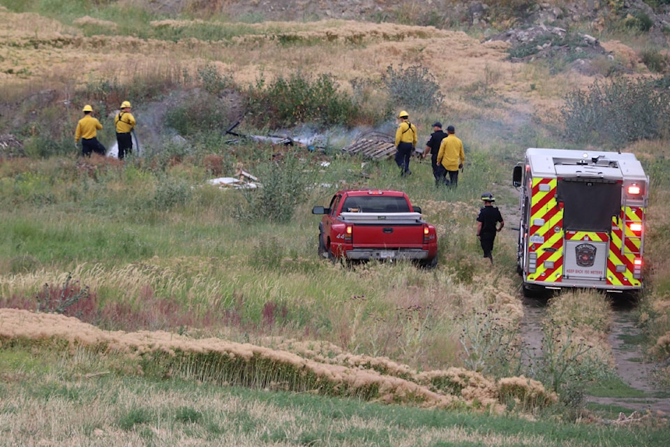 Firefighters extinguish a rubbage fire off Old Kamloops Road Monday July 14.
