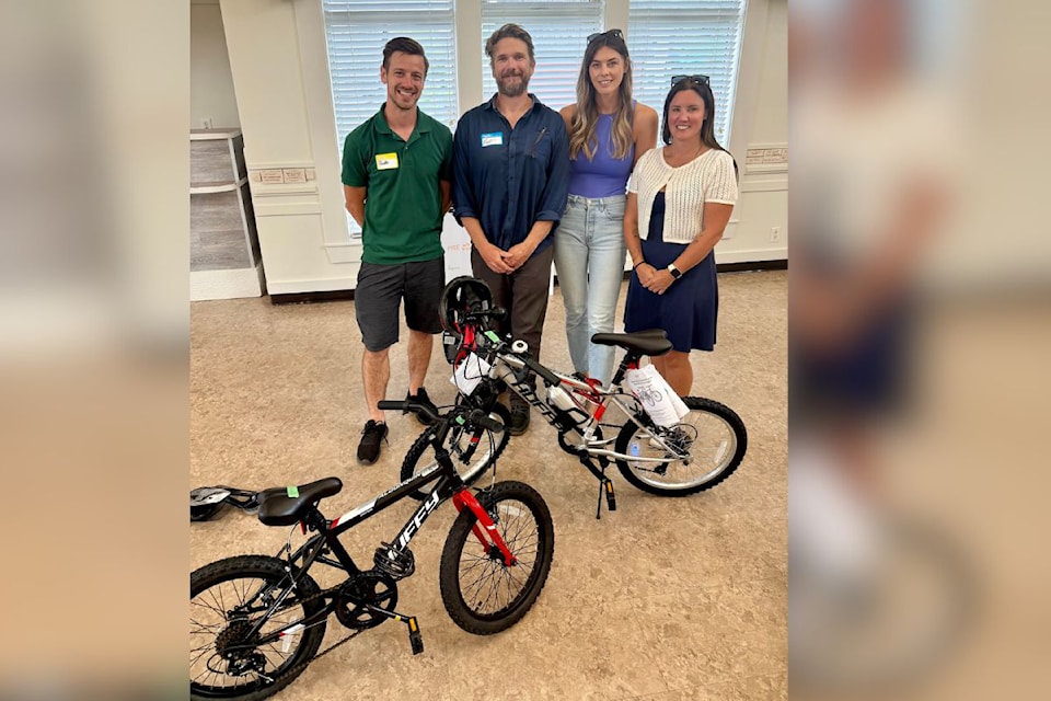 Baxter Bolton, president of KingFisher Boats (from left), and vice-president Kent Beckman,  present bikes made in a team-building exercise to North Okanagan Youth and Family Services Society representatives Lindsay Hadland and Brie DeCenzo.