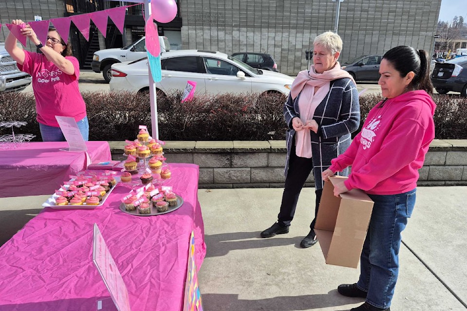 North Okanagan Youth and Family Services Society board director Amanda Clarke (left) puts the finishing touches on the display booth while Sabine Delveaux (centre) and Nilva Castillo wait patiently to buy the first compliment cupcakes Wednesday, Feb. 26, at NOYFSS' annual Pink Shirt Day fundraisers. Funds from the sale of the cupcakes – which sold out – go toward NOYFSS kids' programs, including anti-bullying.