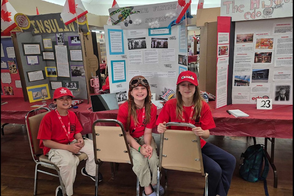 Mission Hill Elementary School Grade 5 students Ezekiel Cabaylo (left) and Emma Hackzell (right) join classmate Naomi Posnikoff at her project on The Flying Seven at the Regional Heritage Fair Friday, April 25, at Vernon's Schubert Centre.