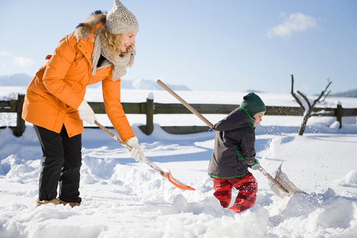 Mother and son digging with snow shovels