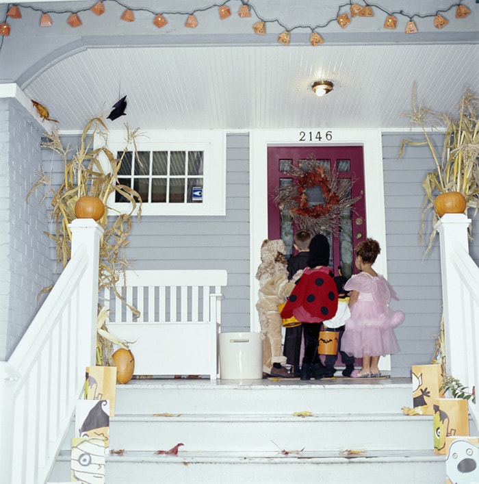 Children (2-8) knocking on door, trick-or-treating, rear view