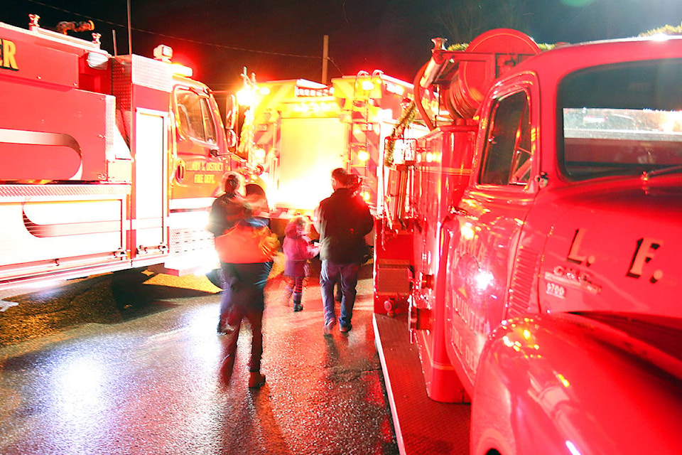 People make their way through glowing Lumby and District Fire Department trucks following the Lumby Christmas Light Up parade Sunday, Dec. 2. (Parker Crook/Morning Star)