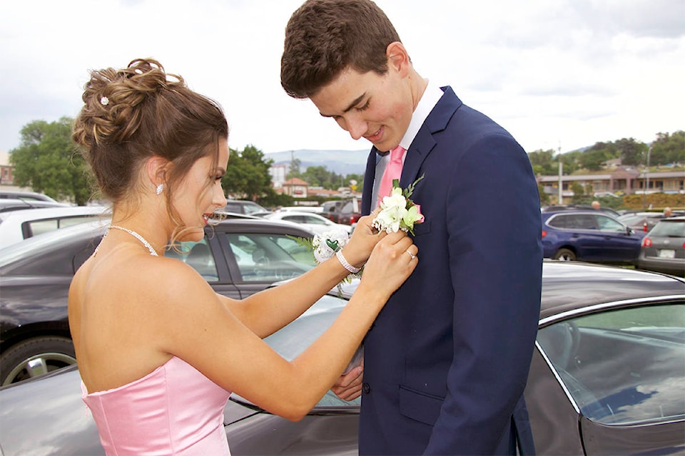 Sophie Borhi pins boutonnière on prom date Jaden Stone. (Brieanna Charlebois - Morning Star)