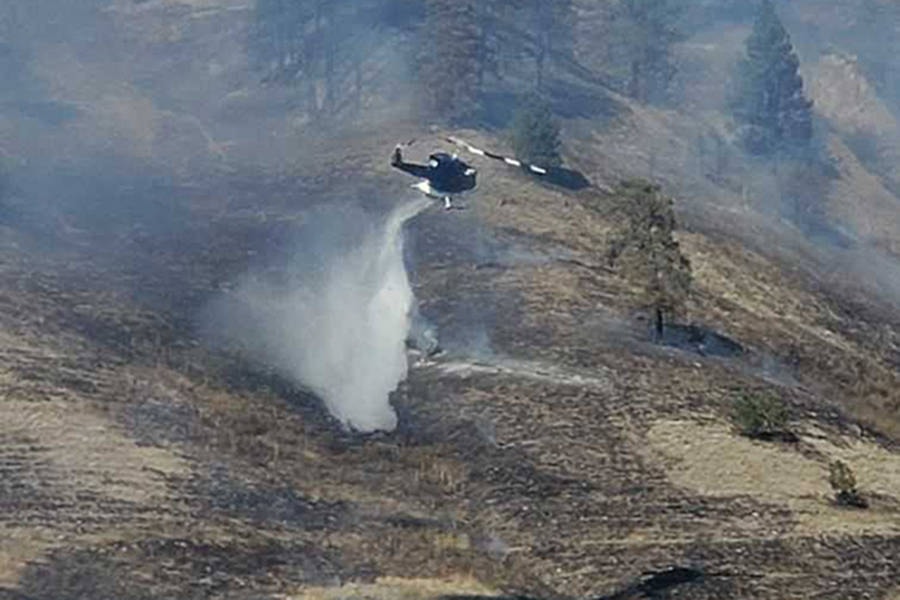 A helicopter drops water on a grass fire south of Vernon off Highway 97 at Westridge Road Monday, Sept. 7. (Shane White photo)