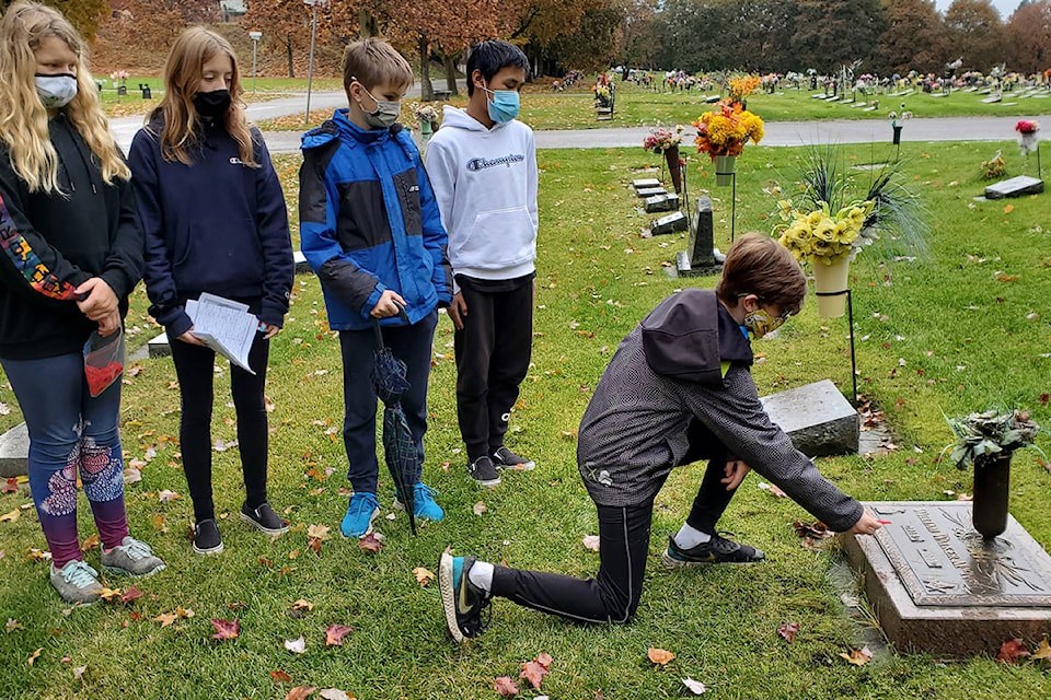 Harwood Elementary Grade 7 students Alexus Wolden (from left), Ashley Kotz, Oliver Williamson and Josh Tran watch as classmate Brady Forsyth places a poppy on the grave of William (Walker) MacNeil in Vernon’s Pleasant Valley Cemetery during the No Stone Left Alone remembrance ceremony Wednesday, Nov. 4. (Roger Knox - Morning Star)