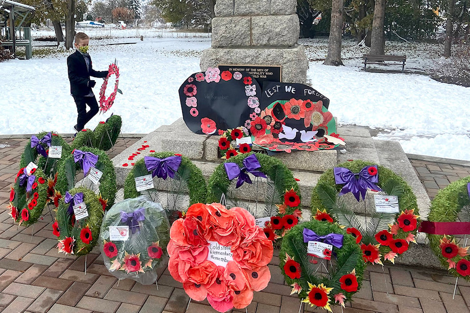 Eight-year-old Jonah McMillan places a paper wreath at the Coldstream Cenotaph Nov. 11, 2020. (Jennifer Smith - Morning Star)
