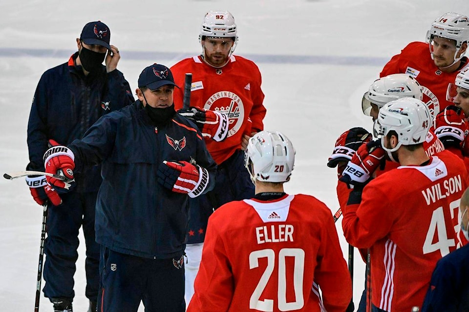 Washington Capitals head coach Peter Laviolette, center left, talks to his players during NHL hockey practice at the MedStar Capitals Iceplex in Arlington, Va., Monday, Jan. 4, 2021. (Ricky Carioti/The Washington Post via AP)