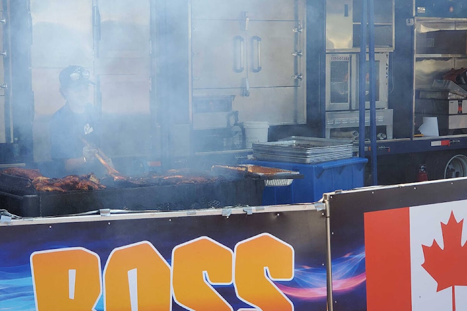 Trent Jolliffe of Boss Hog’s is behind that magical barbecue smoke preparing another order at the Vernon Ribfest Revival Sunday, July 10, at Swan Lake Market and Garden. (Roger Knox - Morning Star)