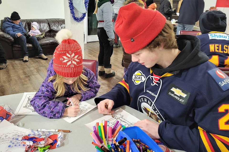 Jane Rutten (6), from Coldstream, left, has fun colouring with Vernon Vipers forward Lee Parks at the Coldstream Community Christmas Light Up Sunday, Dec. 4, at the Coldstream Christian Church. (Roger Knox - Morning Star)