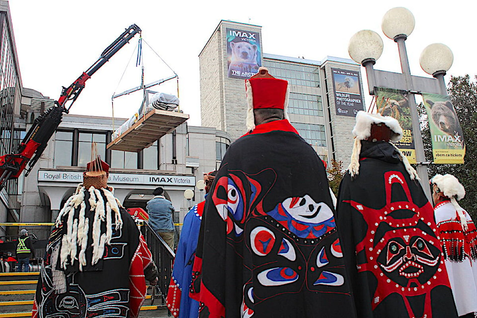 A totem pole is removed and lowered from the Royal B.C. Museum on Feb. 13 as Nuxalk Nation members and others watch on. The totem pole is being repatriated to the Bella Coola territory, its original home before it was taken. (Jake Romphf/News Staff)
