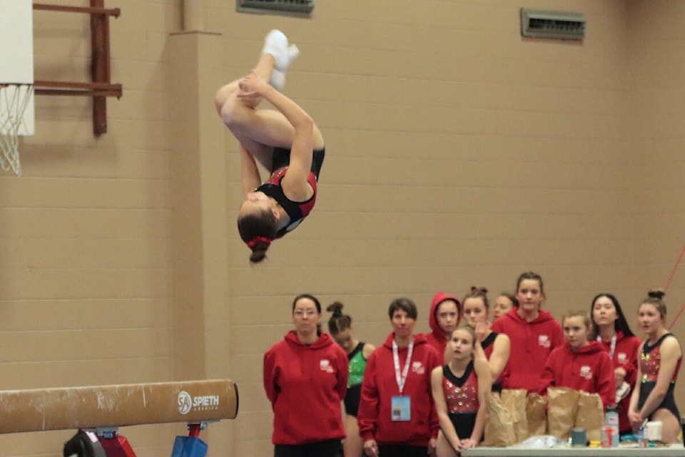 A competitor from the Thompson Okanagan team takes flight off the beam with her coaches and teammates watching during Greater Vernon B.C. Winter Games artistic gymnastics competition Friday, March 24, at the Priest Valley Gym. (Roger Knox - Black Press)