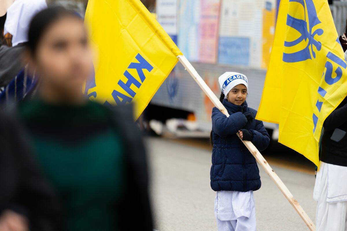 A child carrying a flag during Surrey’s Vaisakhi parade in Surrey on Saturday, April 22, 2023. (Photo: Anna Burns)