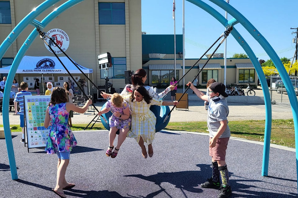 B.C. Education and Child Care Minister Rachna Singh (centre) joins Alexis Park Elementary student Callandra Solhus-Grant (inside,left) and Vernon Monashee MLA Harwinder Sandhu (rear) for a ride on the Oodle Swing, part of the new inclusive and accessible playground equipment at the Vernon School, Tuesday, May 16. Pushing the trio are students Lexa Meise (left) and Brody Panter-Stokes. (Roger Knox - Morning Star)