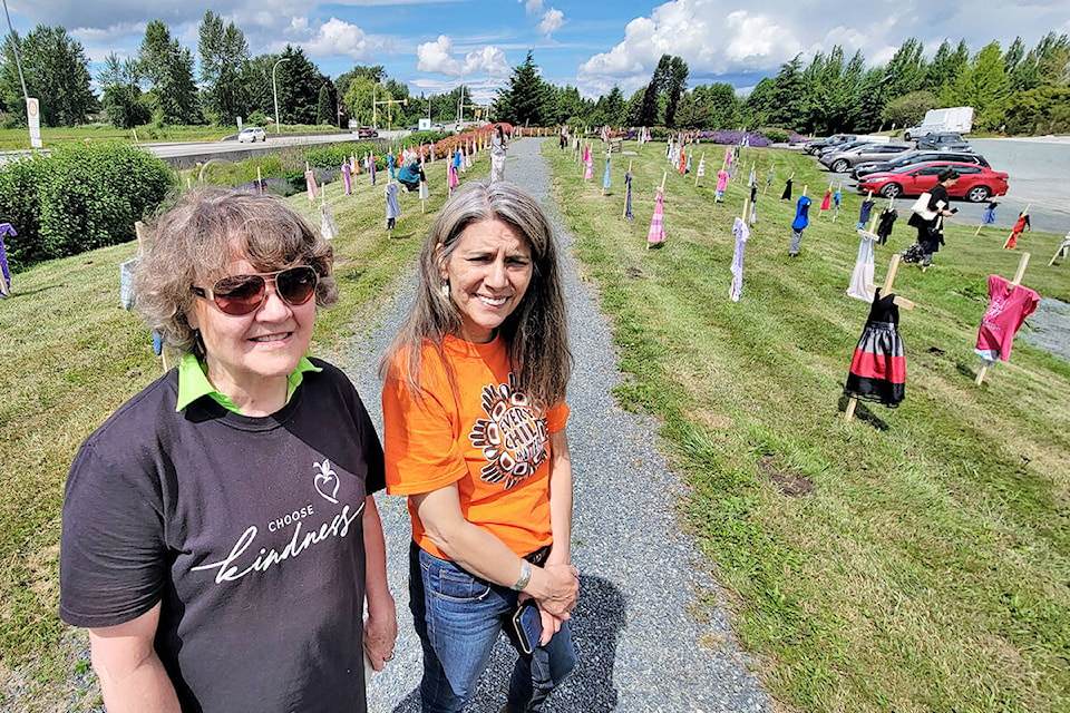 Susan Cairns (left) and Cecelia Reekie, a former Langley school trustee, with the 215 crosses bedecked with children’s clothes placed in memory of the Kamloops residential school victims at the Derek Doubleday Arboretum at 21559 Fraser Hwy. Langley on Tuesday, June 15, 2021. (Dan Ferguson/Langley Advance Times)